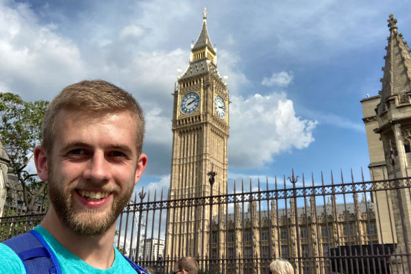 male student standing in front of clock tower