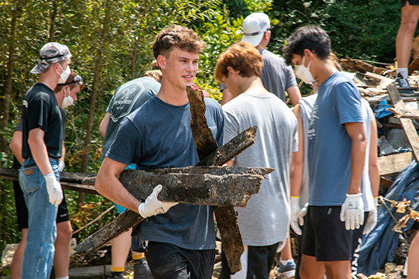 students carrying trash during service project