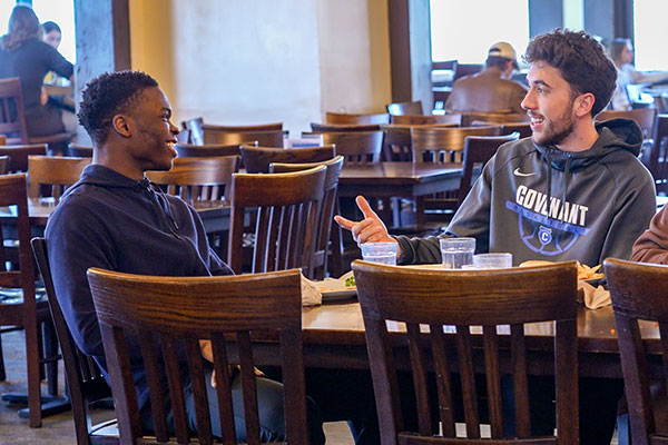 two male students eating lunch and talking