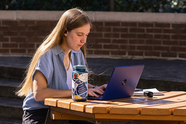 female student on computer outside