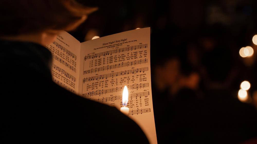 Candlelight illuminating open hymnbook during a Christmas concert