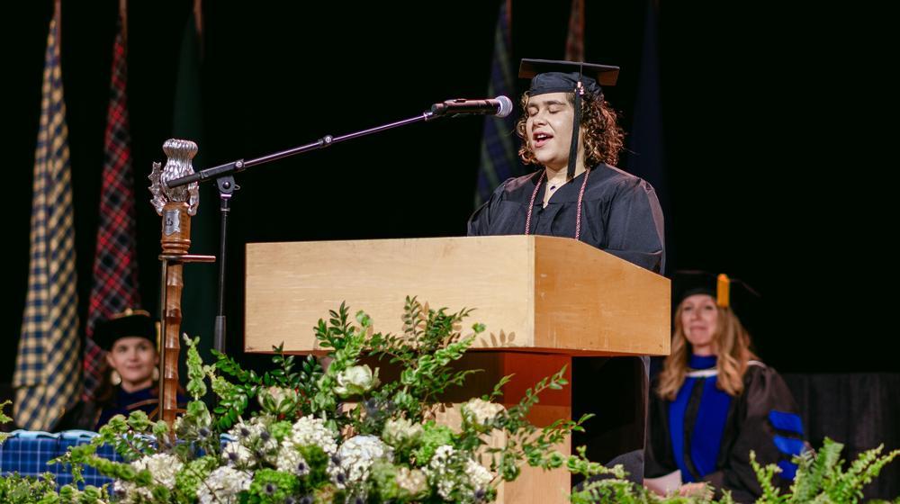 luisa speaking from podium on a stage during commencement
