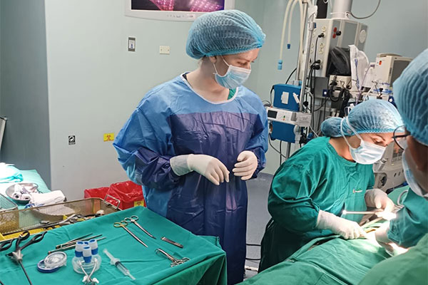 Medical team in surgical attire performing a procedure in an operating room.