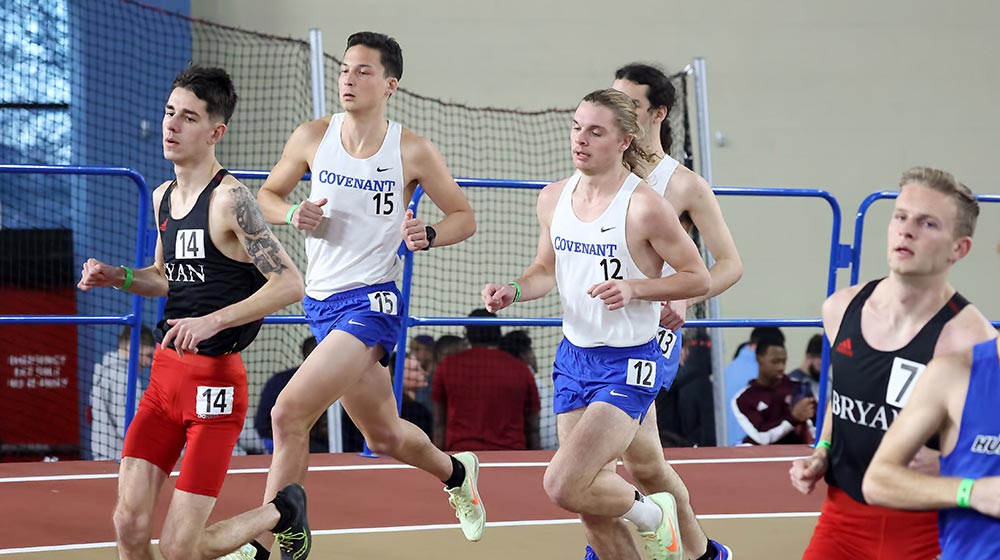 male track and field athletes running on indoor track