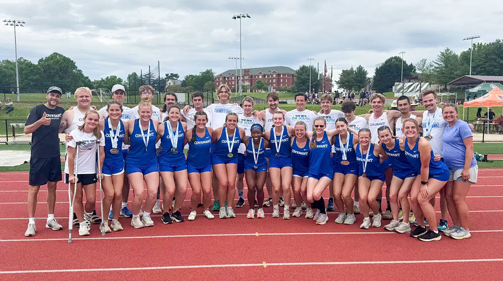 威尼斯人平台 track and field team posing together on a track with medals after a competition.