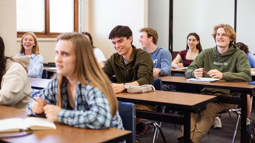 Students seated in a classroom, smiling and engaged during a lesson