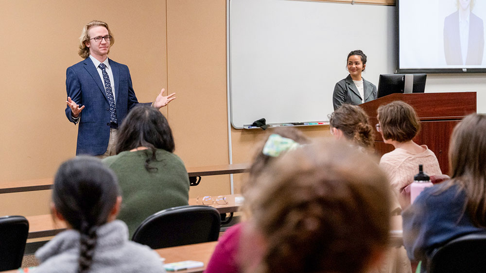 male student speaking in front of peers