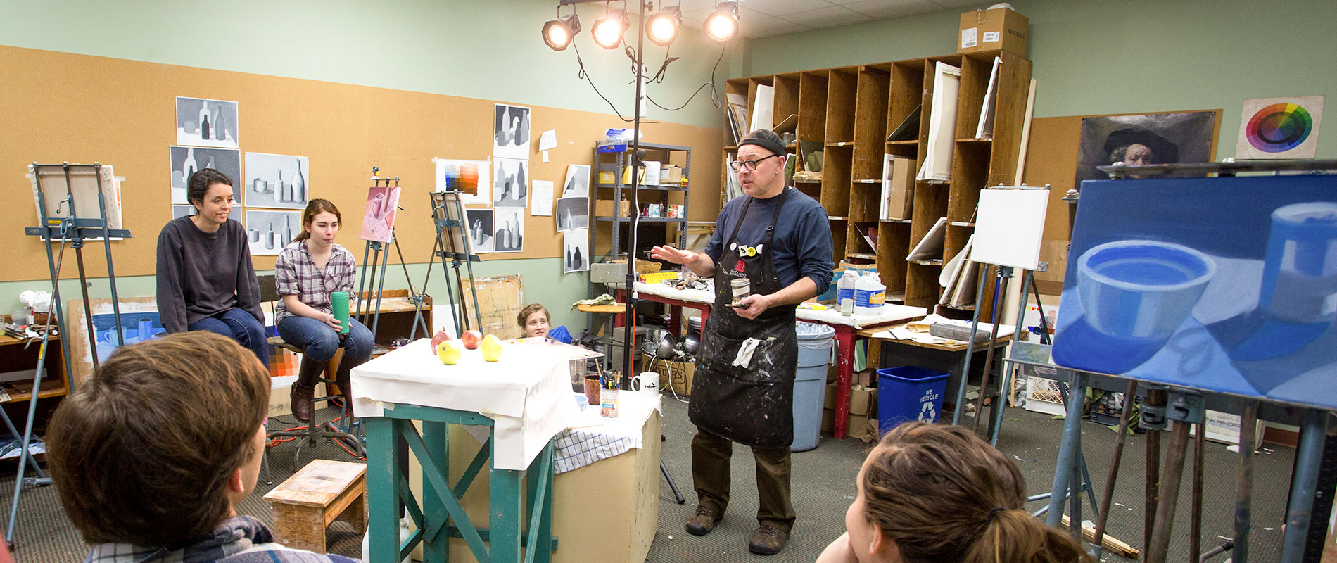 professor teaching painting to students in studio