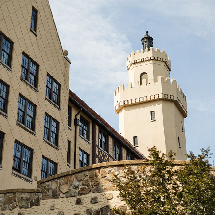 Exterior view of a castle-like dormitory building with a prominent tower and stone walls.